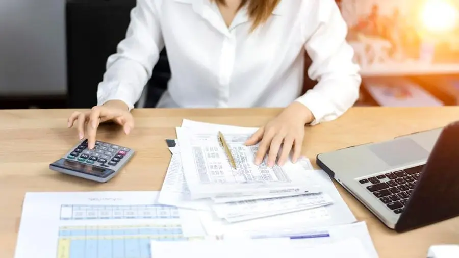Business professional reviewing payroll documents and calculating employee salaries