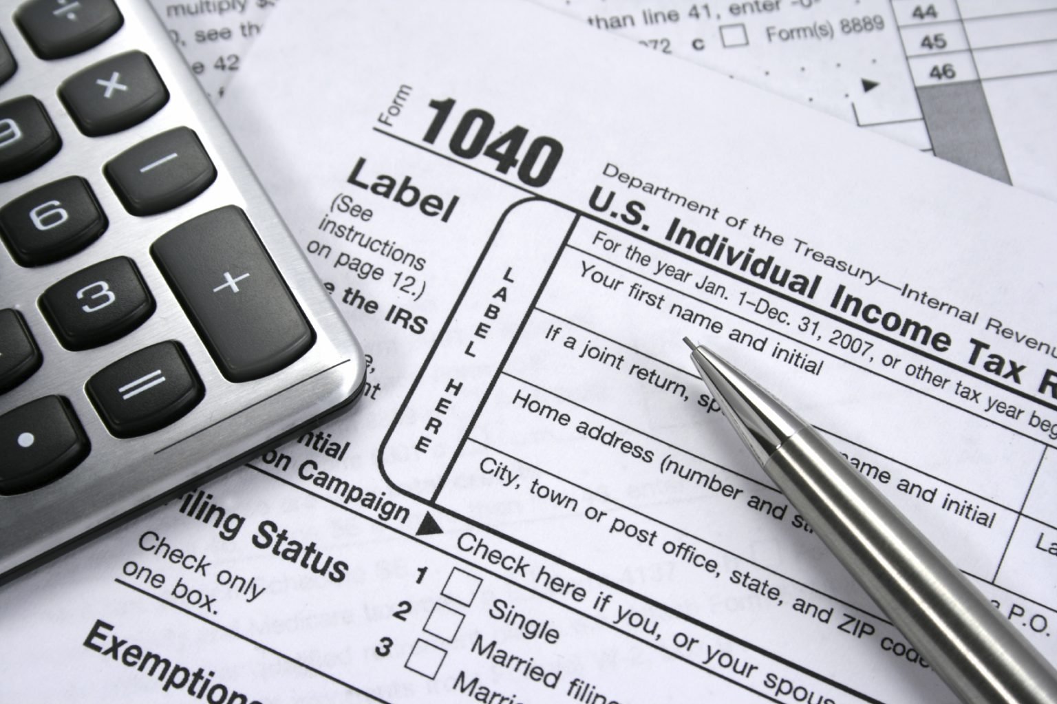 IRS Form 1040 with calculator and pen for individual tax filing and compliance